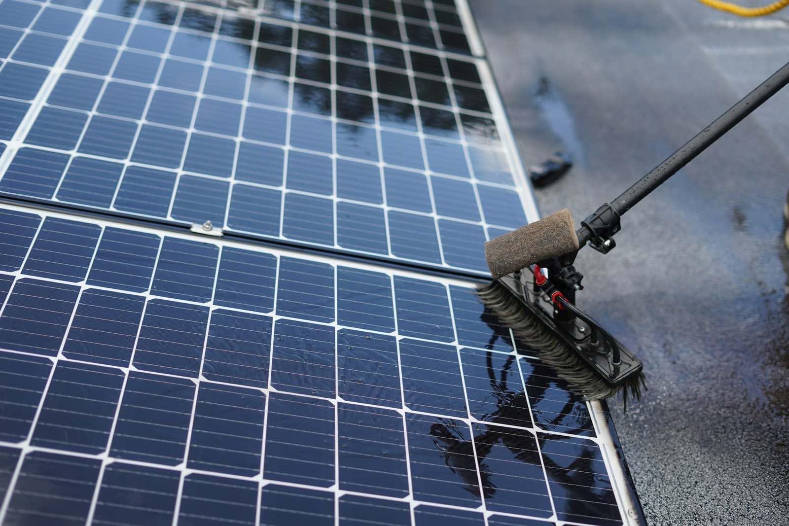 Photovoltaikmodul wird mit einer Waschbürste an einer Teleskopstange gereinigt